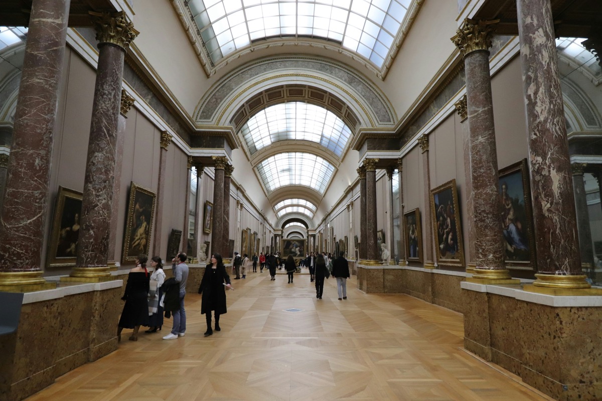 People exploring a museum exhibition hall with framed artwork on the walls