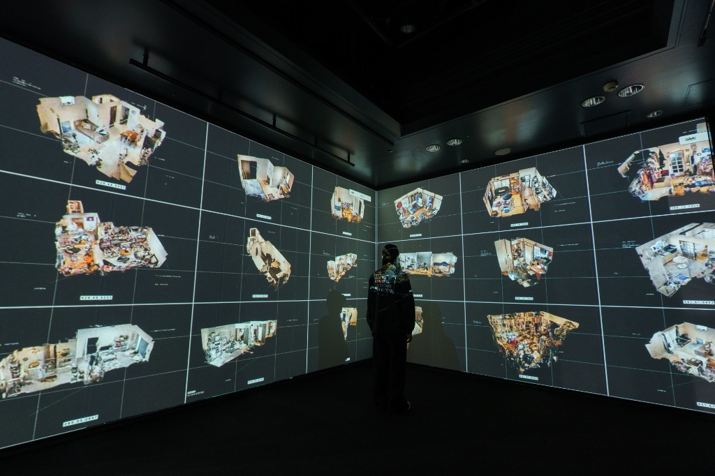 Visitor standing before immersive wrap-around screens displaying 3D scanned Tokyo apartments at the CCBT exhibition