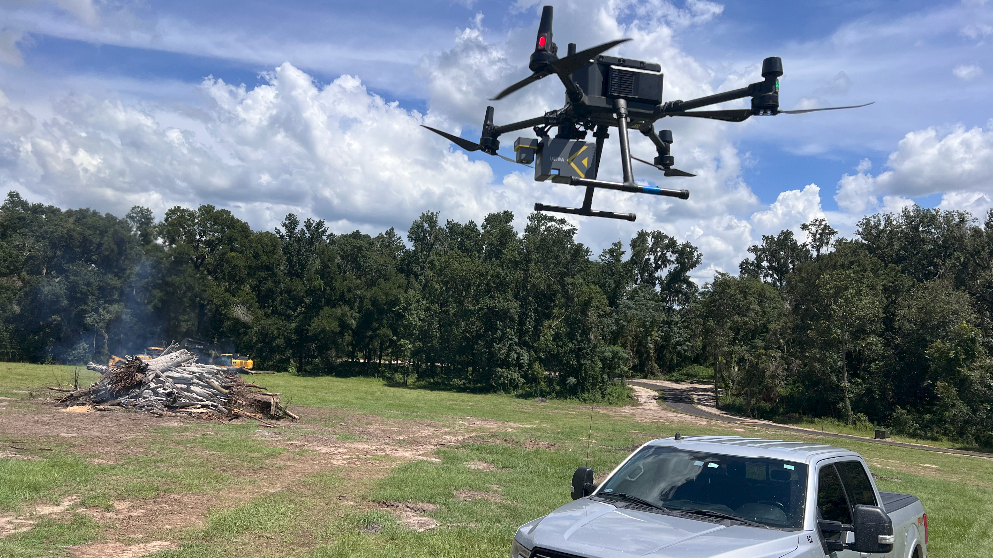 Drone ROCK Ultra LiDAR en action au‑dessus d’un chantier en Floride avec tas de broussailles et engins lourds